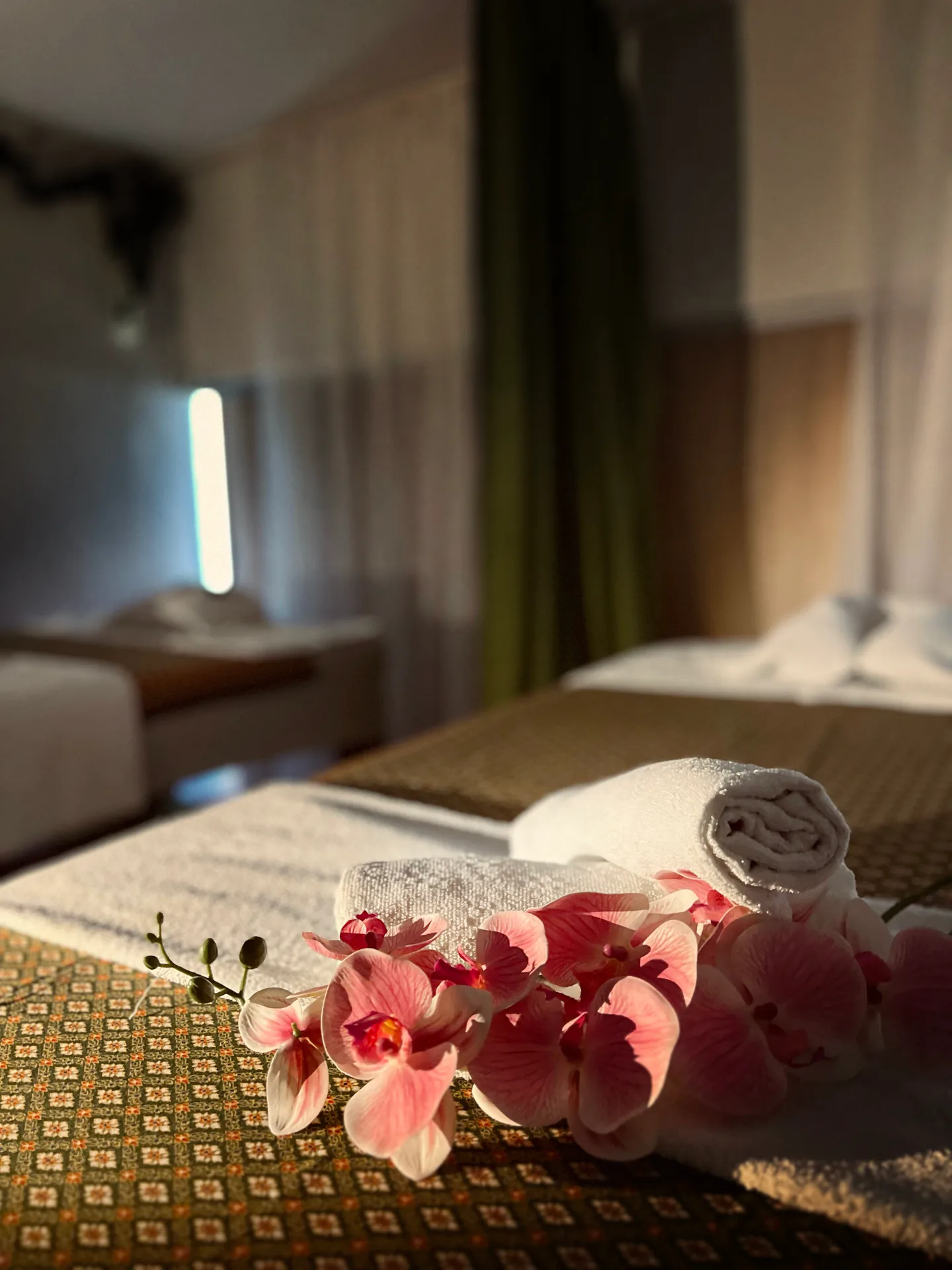 Pink orchids and folded towels in a tranquil treatment room